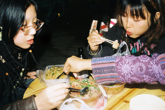 Young women enjoying street food at night market