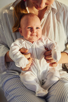 Smiling baby sits on lap of mother in striped clothing 