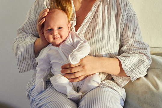 Smiling baby sitting on lap of adult in home 