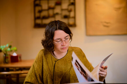 Engaged Reader Exploring a Menu in a Tea Room Setting
