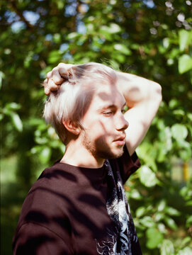 a blond man in a tree shadow