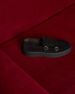 Black shoe rests on red surface in a simple setting