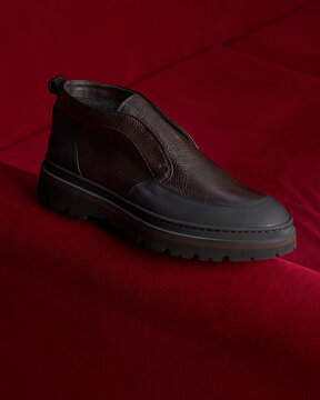 Brown slip-on shoes placed on a red surface