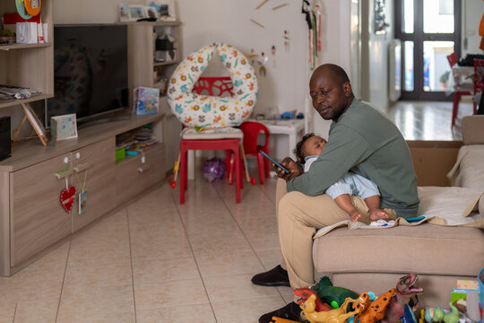 Thoughtful father resting with his sleeping child in the living room