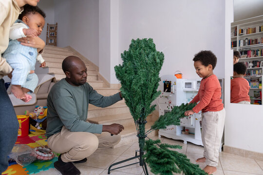 Family preparing for the holidays by assembling the Christmas tree 