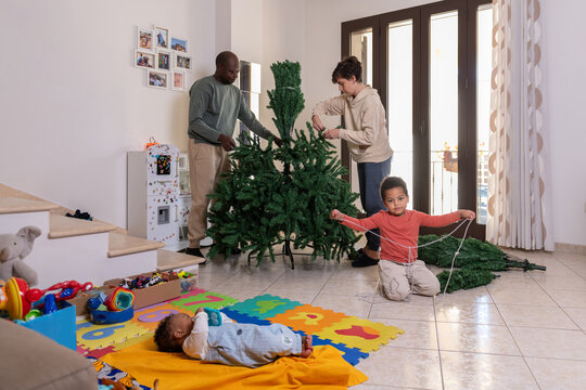 Family assembling a Christmas tree together in the living room