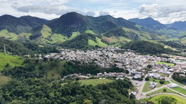 Aerial drone view of Alfredo Chaves city in Esp&iacute;rito Santo, Brazil. Urban area surrounded by green mountains, hills and rural landscape under blue sky, typical countryside scenery.
