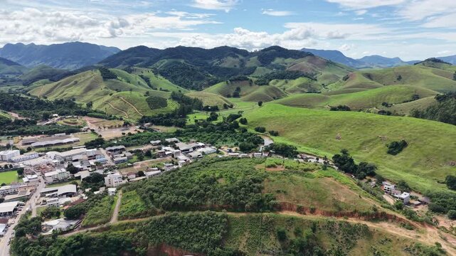 Aerial drone view of Alfredo Chaves city in Esp&iacute;rito Santo, Brazil. Urban area surrounded by green mountains, hills and rural landscape under blue sky, typical countryside scenery.
