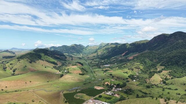 Aerial drone view of Alfredo Chaves city in Esp&iacute;rito Santo, Brazil. Urban area surrounded by green mountains, hills and rural landscape under blue sky, typical countryside scenery.