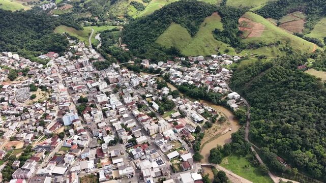 Aerial drone view of Alfredo Chaves city in Esp&iacute;rito Santo, Brazil. Urban area surrounded by green mountains, hills and rural landscape under blue sky, typical countryside scenery.