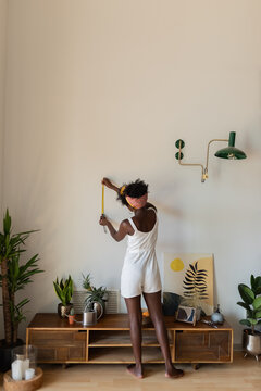 Woman measuring wall for hanging picture