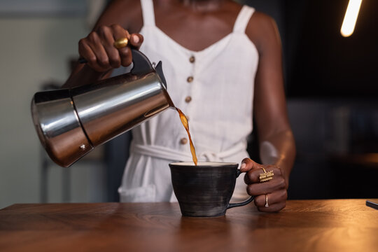 Woman pouring coffee in ceramic cup 