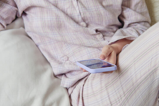 Person wearing a cozy lavender pajama set using their phone 