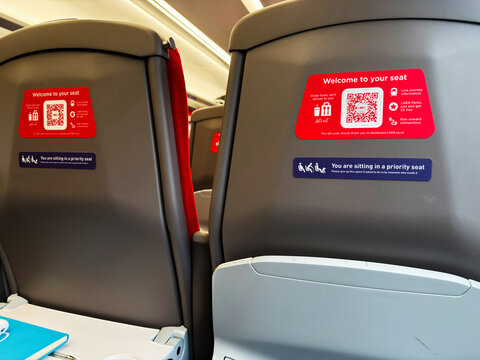 Train seats with welcome to your seat signs and priority seat notices on a modern LNER service in UK. LNER Trains.