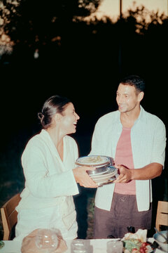 Smiling couple collecting dinner plates