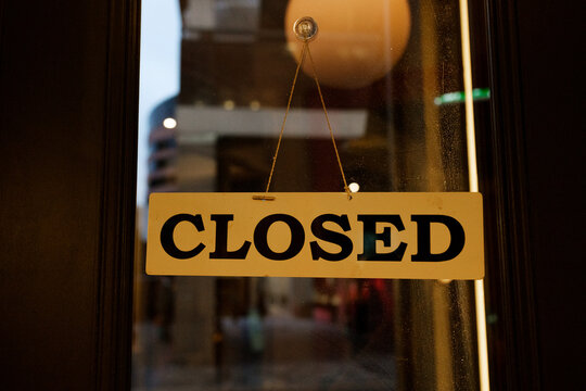 Closed Sign Hanging on Glass Door