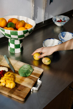 Anonymous hand picking a passion fruit from a countertop