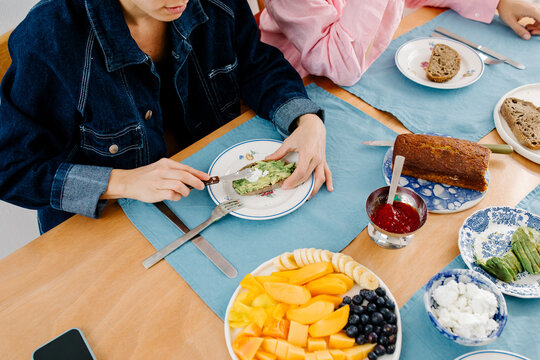 Unknown woman&rsquo;s hands spreading avocado on toast