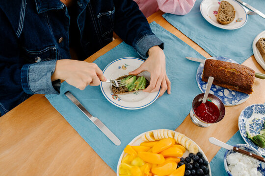 Unknown woman spreading avocado on toast