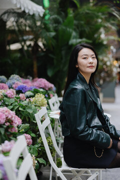 Woman Sitting by Flower Garden in Outdoor Cafe