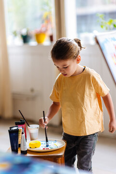 Young Child Painting At Home With Art Supplies