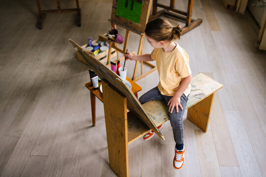 Boy Painting At Easel In Art Studio