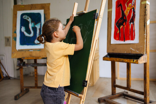 Young Child Drawing On Chalkboard In Art Studio