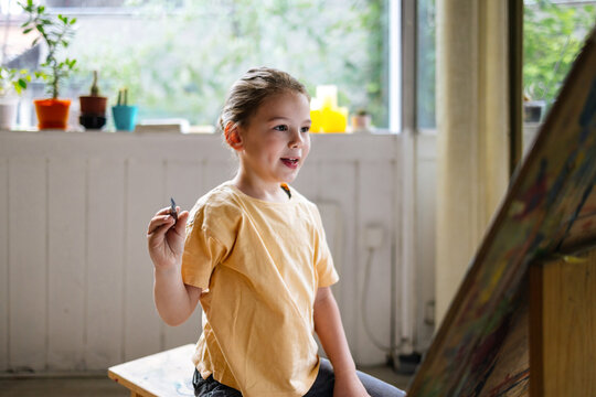 Young Boy Painting Joyfully At Studio Easel