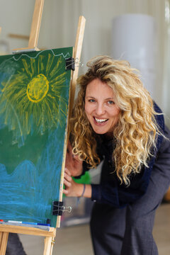 Joyful Artist Woman Painting Sun On Chalkboard