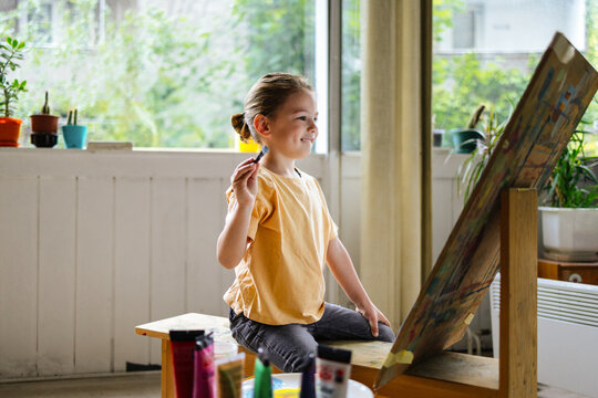 Young Boy Painting Joyfully At Easel In Studio