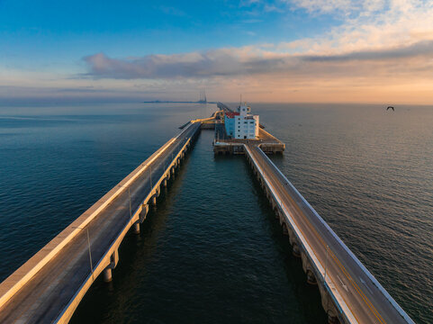 Aerial view of the long Progreso Pier and its white building stretching into the ocean under a golden sunset sky in Yucatan, Mexico.
