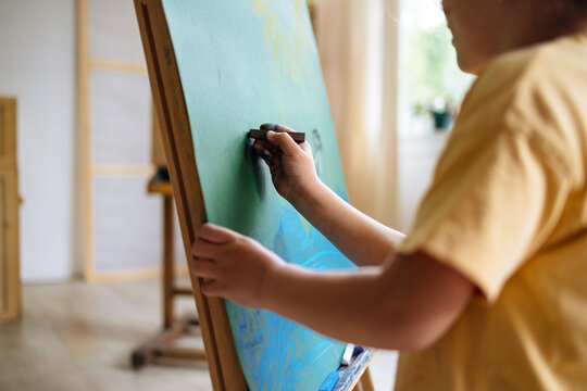 Young Artist Painting On Easel With Chalkboard