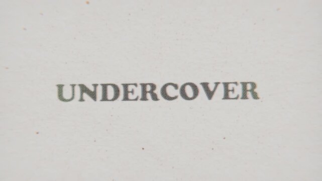 CMYK Halftone Text Undercover Printed on Changing Paper with Vintage Stop Motion Effect.