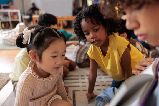 Children reading a book together in a classroom setting.
