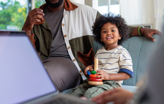 Father and child playing with toy rings near laptop.