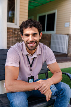 Smiling man with name tag sitting on a bench.