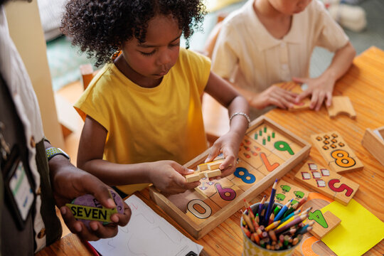 Children learn math with wooden puzzles and teacher.