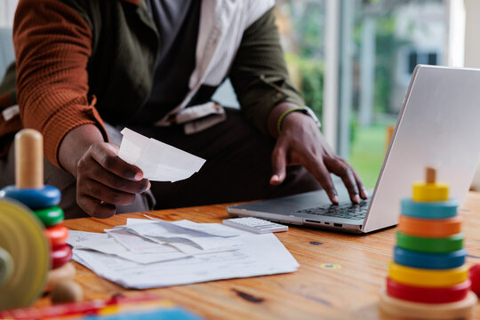 Man paying bills online with toys nearby.