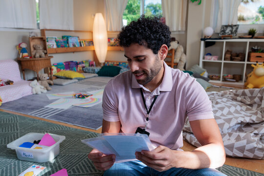 Man reviews papers in a colorful, child-friendly learning environment.