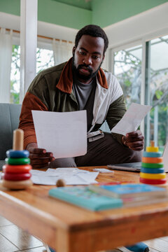 Man reviews bills at home with children's toys.