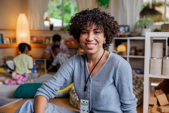 Smiling teacher in a bright, playful classroom setting.
