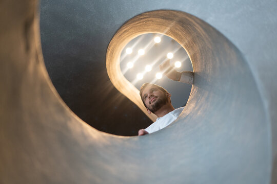 Man Peering Down Modern Concrete Spiral Staircase