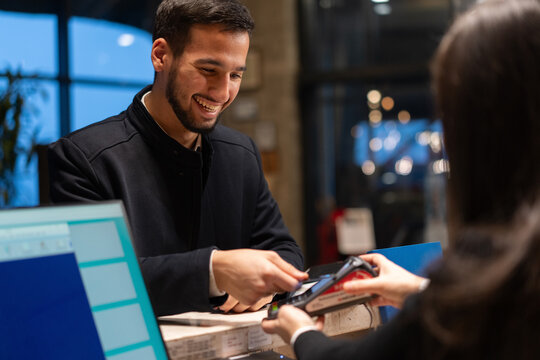 Smiling Businessman Making a Contactless Payment at Hotel Reception