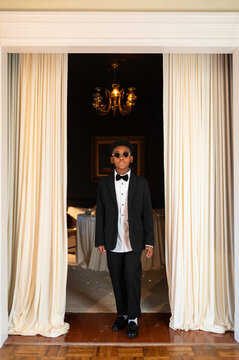 Boy in Formal Wear Stands in Doorway at a Celebration Event