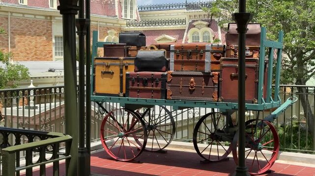 Stacked vintage suitcases displayed on a historic railway platform evoke classic travel nostalgia. Old-fashioned architecture and period details create a timeless atmosphere.
