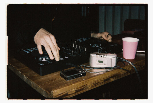 DJ mixing at party with retro camera gear  
