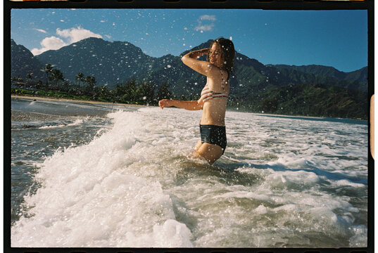 tourist having fun swimming at the beach splashing shoreline kauai 