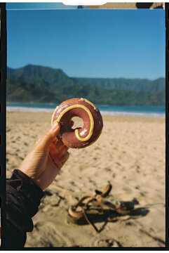 hand holding donut on beach