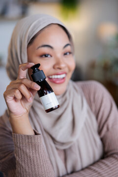 Woman in hijab promotes organic skincare product.