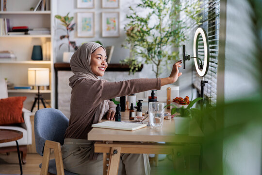 Muslim woman filming beauty tutorial with ring light.